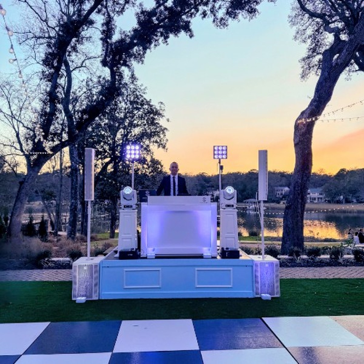 All-white DJ booth on an 8x8 stage at a private home at sunset
