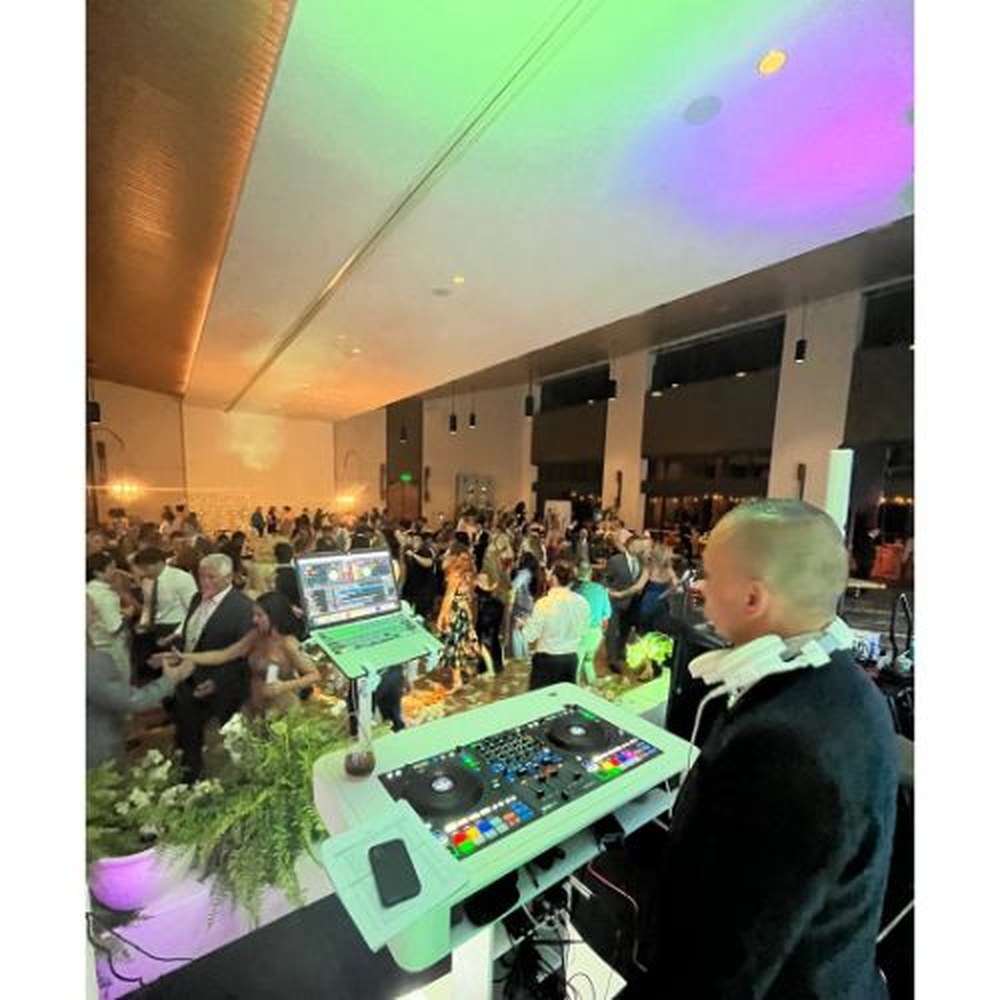 DJ mixing above a packed reception hall